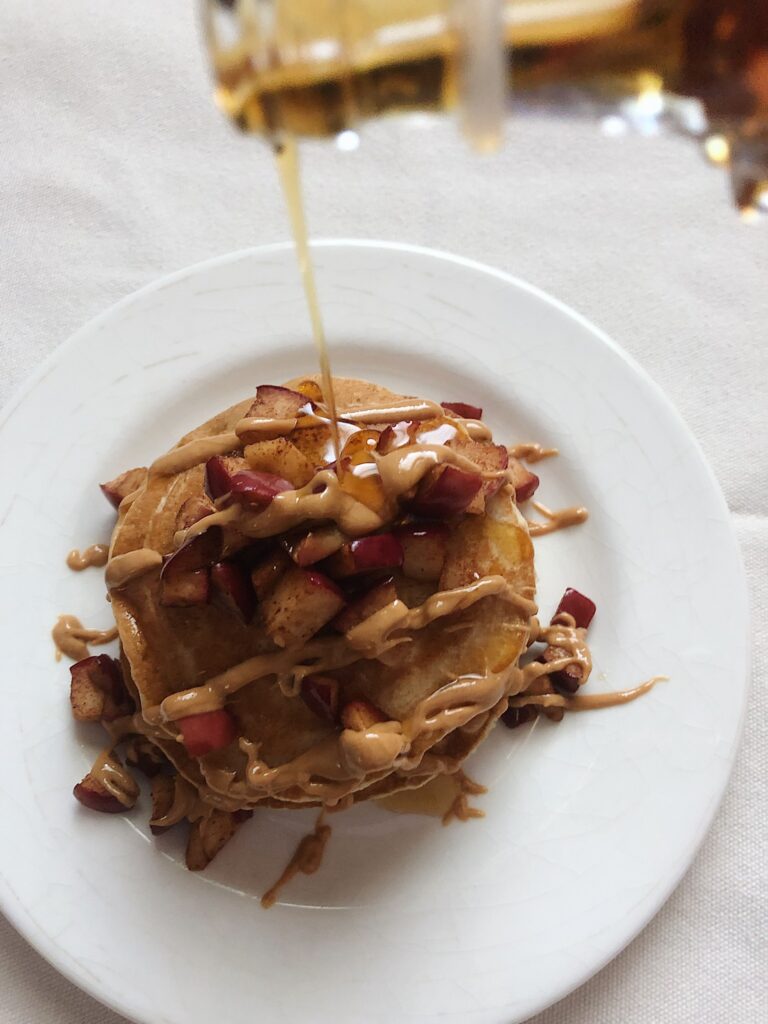 pancake stack with fruit and maple syrup bottle pouring