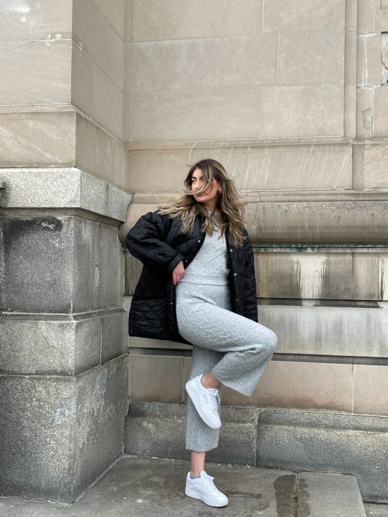 girl posing in outfit picture against light concrete building